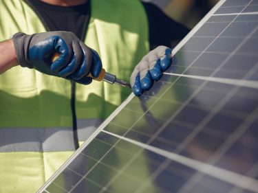 Man in a white helmet near a solar panel