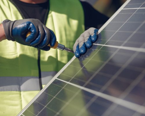 Man in a white helmet near a solar panel